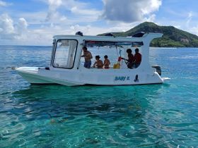 A family enjoys a day on the water aboard the 'Baby K,' surrounded by stunning turquoise waters — perfect for memorable adventures and fun activities.