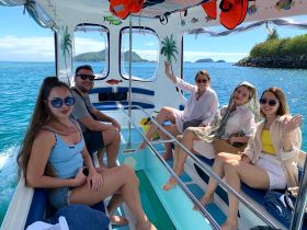 A cheerful group of friends enjoys a sunny day on a boat, surrounded by stunning ocean views — perfect for a fun day out on the water.