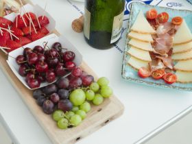 A beautifully arranged charcuterie board featuring fresh fruits, cheese, and cured meats, perfect for enjoying on a boat trip with friends or family.