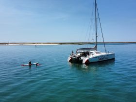 Two individuals enjoy kayaking near a catamaran, showcasing a perfect day of water activities and adventure.