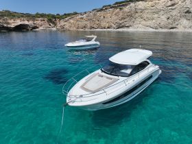 A stunning aerial view of two elegant yachts anchored in crystal-clear waters, showcasing the beauty of a serene coastal landscape.