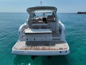 A stunning view of the back of a yacht anchored in crystal-clear waters, showcasing its sleek design and inviting deck space.