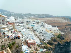 A scenic view of a coastal town with white buildings, showcasing a lively atmosphere with people present. The image captures the essence of a popular tourist destination.