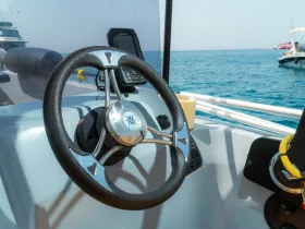 A close-up view of the helm and console of a boat, showcasing the steering wheel and navigation equipment, perfect for those looking to explore the open waters.