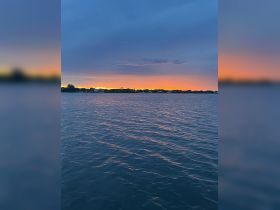 A serene sunset over calm waters, showcasing a picturesque landscape perfect for evening boat cruises.