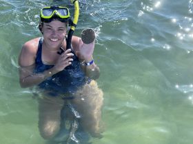 A smiling snorkeler holds a sea star while enjoying a vibrant underwater experience — perfect for marine life enthusiasts and adventure seekers.