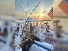 A lively group of friends enjoys a sunset celebration aboard a boat, showcasing the perfect atmosphere for summer parties on the water.