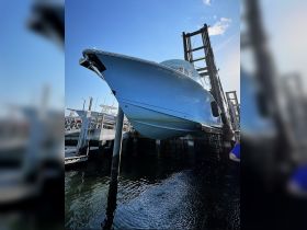 A stunning blue yacht is being lifted at the dock, showcasing its sleek design against a clear sky — perfect for luxury boating experiences.
