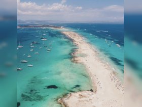 A stunning aerial view of a picturesque coastline with numerous boats anchored in crystal-clear waters, showcasing the beauty of a tropical paradise.