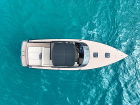 Aerial view of a sleek speedboat gliding through crystal-clear turquoise waters, showcasing its elegant design and spacious seating.