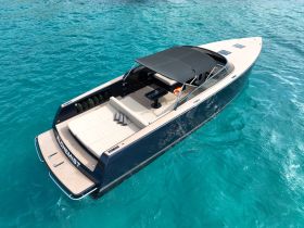 A stunning aerial view of the 'Alchemist' yacht gliding through crystal-clear waters, showcasing its sleek design and spacious deck — perfect for luxury outings.