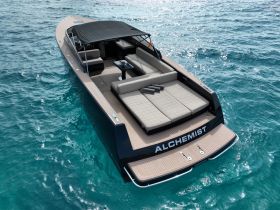 A stunning aerial view of the 'ALCHEMIST' yacht cruising through crystal-clear waters, showcasing its sleek design and spacious deck, perfect for luxury outings.