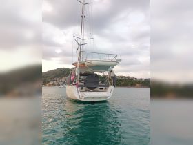 A stunning view of a yacht from the rear, showcasing its sleek design against a backdrop of serene waters and a picturesque shoreline.