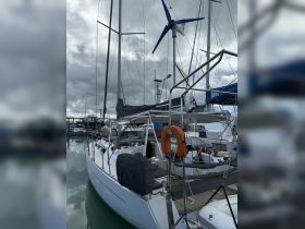 A sleek sailboat docked at the marina, showcasing its structure and features, with a crew member visible on board.