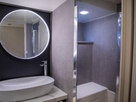 A modern boat bathroom featuring a sleek sink and shower area, showcasing the stylish interior design typical of luxury vessels.