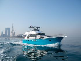A stunning yacht glides through calm waters with a vibrant city skyline in the background, showcasing the perfect blend of luxury and urban scenery.
