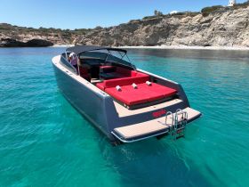 A sleek speedboat anchored in crystal-clear waters, showcasing its modern design and comfortable seating — perfect for a day of relaxation on the water.