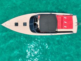 Aerial view of a sleek speedboat resting on crystal-clear waters, showcasing its elegant design and spacious seating — perfect for a day of fun on the water.
