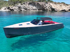 A sleek boat glides through crystal-clear waters, showcasing a scenic backdrop of rocky cliffs — perfect for a day of adventure on the water.