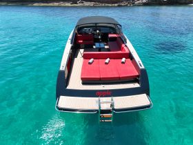 A stunning aerial view of a sleek speedboat anchored in crystal-clear waters, showcasing its luxurious red seating and modern design — perfect for summer adventures on the water.