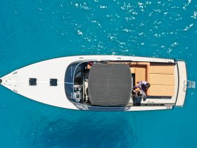 An aerial view of a stylish boat with guests relaxing on the deck, showcasing the perfect setting for a day on the water.