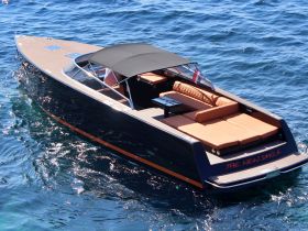 A stunning aerial view of 'The New Smile' yacht cruising through clear blue waters, showcasing its sleek design and spacious seating area.