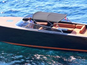 A sleek yacht glides through clear waters, showcasing its elegant design and spacious seating area, perfect for luxury cruising.
