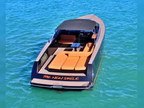A stunning speedboat named 'The New Smile' glides through clear waters, showcasing its sleek design and spacious seating, perfect for luxury outings on the water.