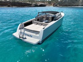 A sleek speedboat named 'Sea Sharty' glides through crystal-clear turquoise waters, showcasing its modern design and spacious deck, perfect for a day on the water.