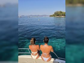 Two friends enjoy the stunning ocean view from the deck of a boat, perfect for a relaxing day on the water.