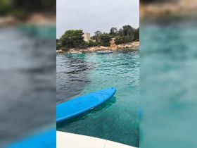 A scenic view of a beach with people enjoying the water, featuring a blue kayak in the foreground — perfect for a day of relaxation and water activities.