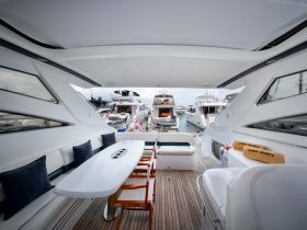 A stylish interior view of a yacht's cabin featuring comfortable seating and a sleek table, perfect for relaxing or dining while enjoying the marina ambiance.