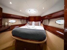 A cozy cabin interior of a boat featuring a comfortable bed and elegant wood finishes, perfect for relaxing during a nautical getaway.