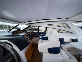 A sleek interior view of a yacht's helm and seating area, showcasing modern design and comfort for an enjoyable boating experience.
