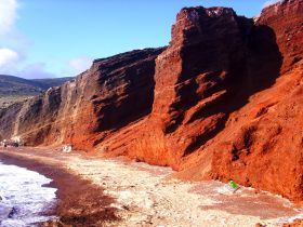 A scenic view of a rugged coastline with striking red cliffs, showcasing the natural beauty of the landscape.