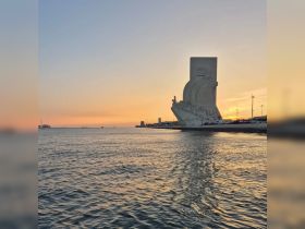 A stunning sunset view over the water, featuring a prominent landmark silhouetted against the colorful sky — perfect for capturing the beauty of coastal destinations.