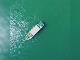 Aerial view of a boat cruising through clear turquoise waters, showcasing its sleek design and vibrant deck.