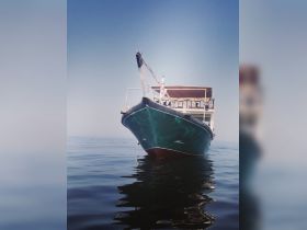 A striking view of a boat captured from the front, gliding smoothly over calm waters, showcasing its elegant design and tranquil surroundings.