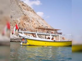 A vibrant yellow boat with guests enjoying the ocean, showcasing a perfect day for snorkeling and group fun in a picturesque setting.