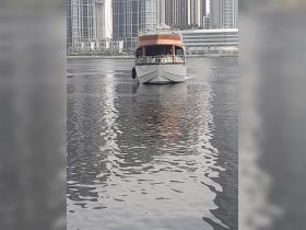 A striking view of a yacht cruising through calm waters, framed by modern skyscrapers — perfect for showcasing luxury boating experiences.