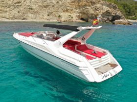 A sleek speedboat named 'La Gata' glides through crystal-clear waters, showcasing its stylish design against a stunning coastal backdrop.