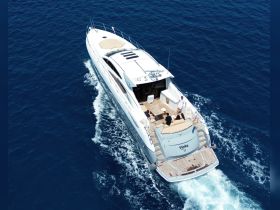 Aerial view of a stylish yacht named 'Vicky II' cruising through deep blue waters, with guests enjoying the ride on deck — perfect for luxurious outings and group adventures.