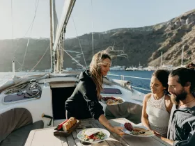 A group enjoys a delightful meal on deck while sailing, showcasing the perfect blend of gourmet dining and scenic views on the water.
