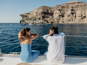A couple enjoys a serene moment aboard a boat, overlooking stunning coastal cliffs and the sparkling ocean — perfect for romantic getaways or scenic tours.
