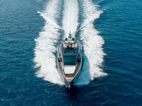 A stunning aerial view of a luxury yacht cruising through vibrant blue waters, showcasing its sleek design and powerful presence on the open sea.
