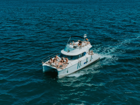 A lively group enjoys a day on a yacht, soaking up the sun and waves while cruising through the beautiful blue waters.
