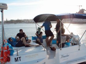 A lively group enjoys drinks aboard a catamaran, capturing the essence of a fun day on the water with friends.