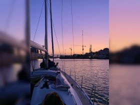 A serene sunset view from a sailboat, showcasing the city skyline and creating a picturesque backdrop for a memorable sailing experience.