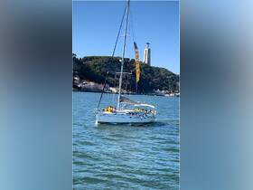 A lively group enjoys a sailing trip on a yacht, with the iconic Christ the King statue in the background, showcasing the beauty of the Lisbon coastline.
