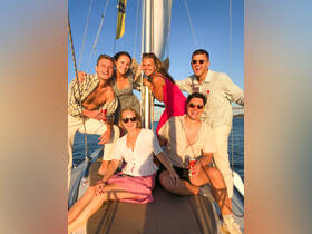 A joyful group of friends poses on the deck of a yacht, celebrating under the warm glow of sunset — perfect for memorable outings and adventures on the water.